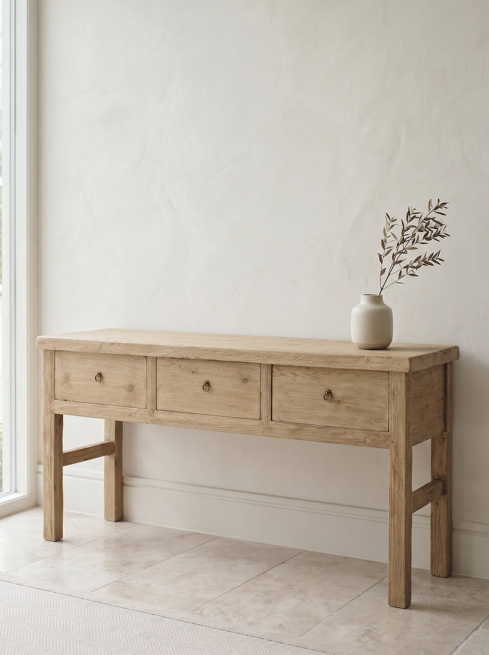 Wooden console table with three drawers against a white wall.