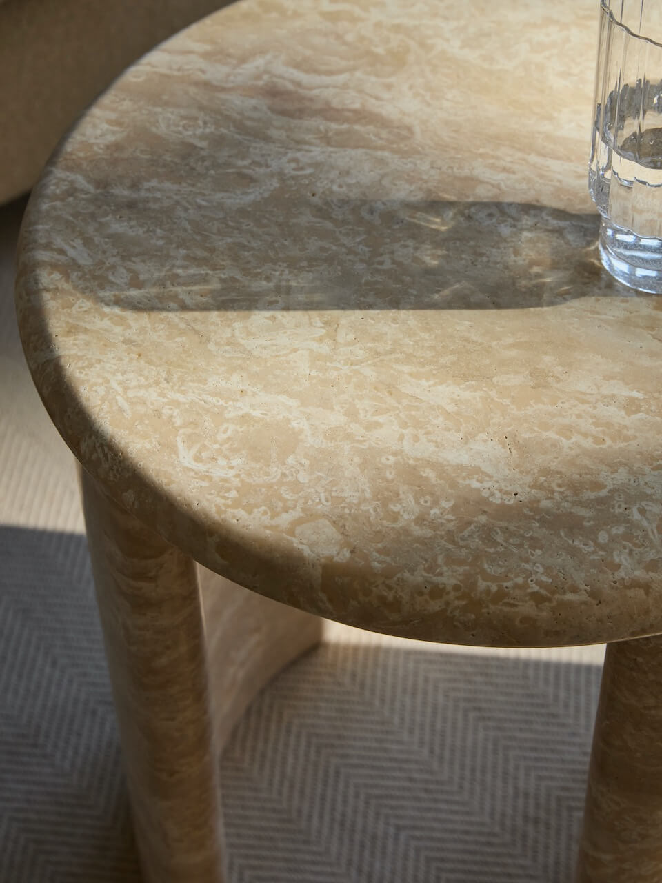 Round stone table with a glass of water on a textured floor