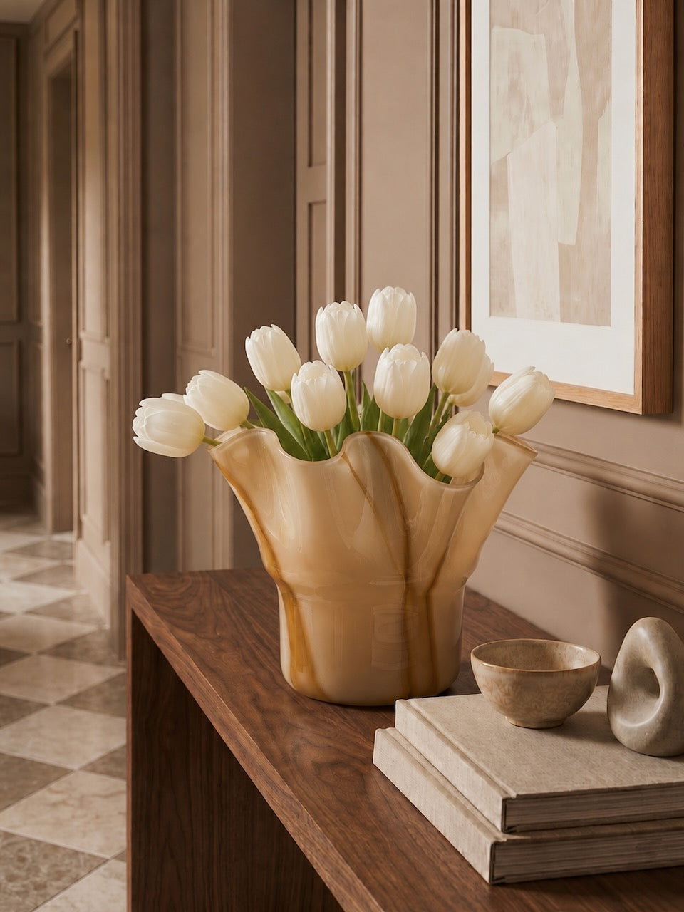 Vase with white tulips on a wooden surface in a room with a mirror and books.