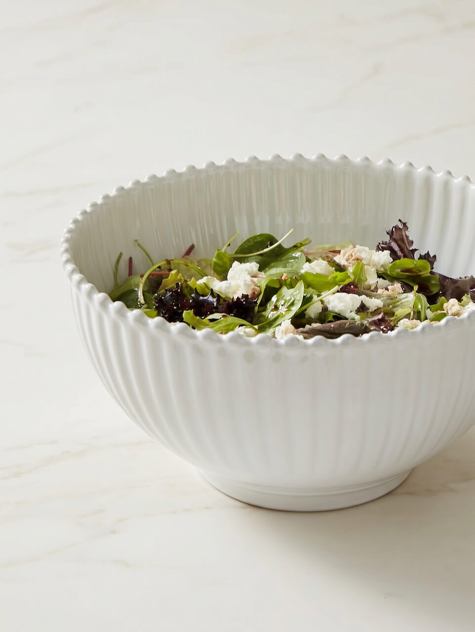 White bowl filled with a salad on a light background