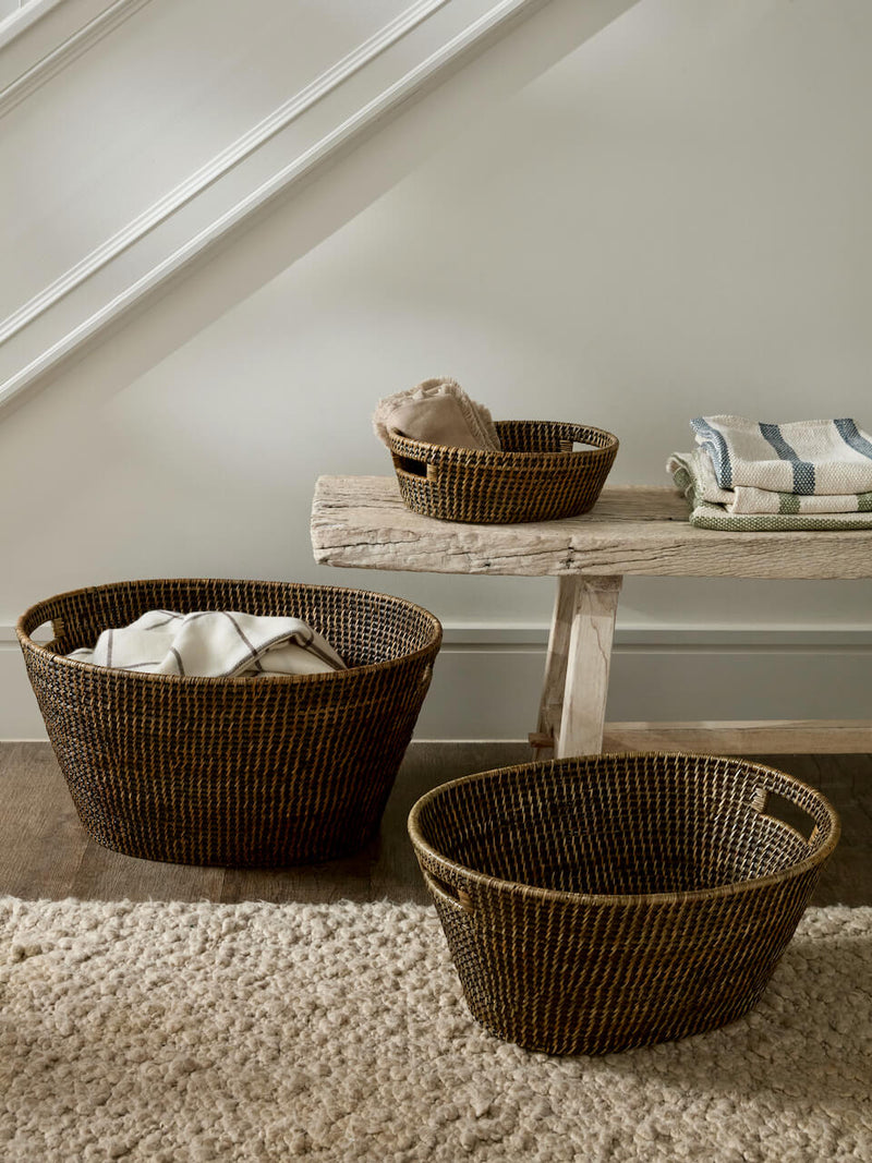 Ceres antique brown rattan basket set in multiple sizes styled in neutral home with bench and textiles, woven storage and laundry baskets UK