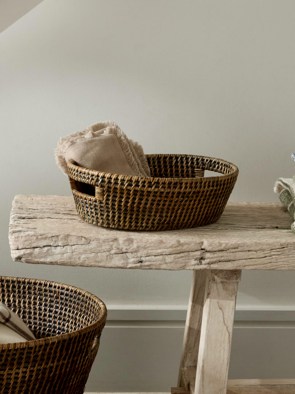 Ceres antique brown rattan basket with handles styled on rustic wooden bench with folded linen, woven storage basket natural home decor UK