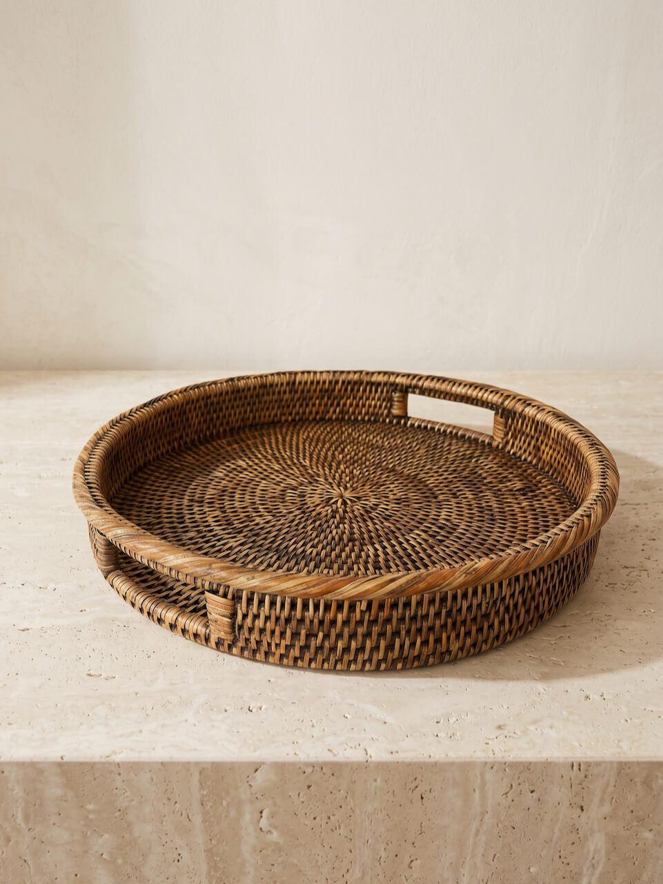 Woven rattan tray on a light stone surface with a neutral background