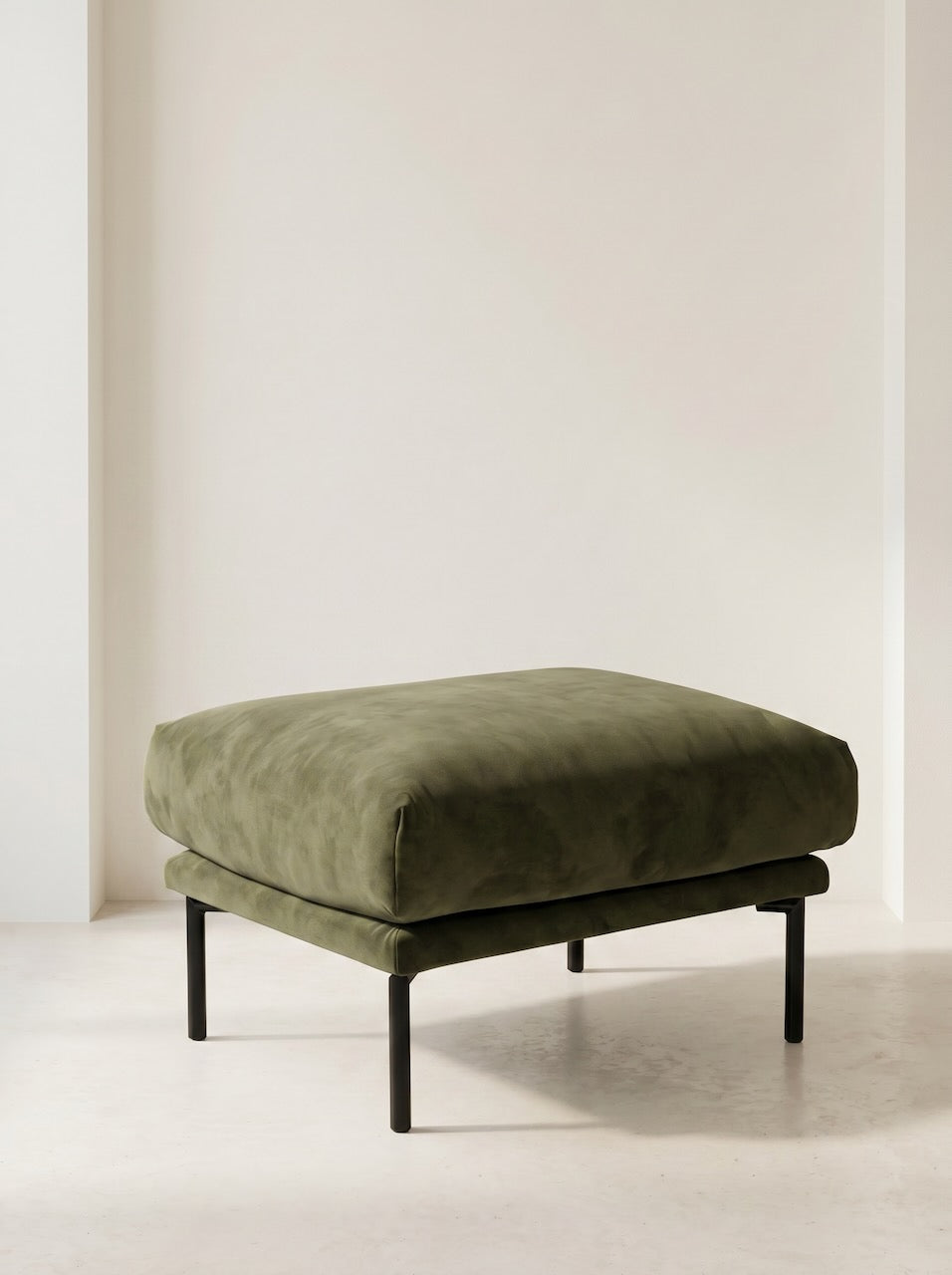 Green upholstered ottoman with black legs on a light background